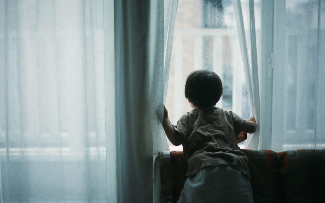 child looking out of a rainy window